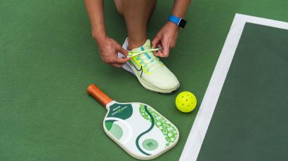 Pickleball athlete tying shoe in court